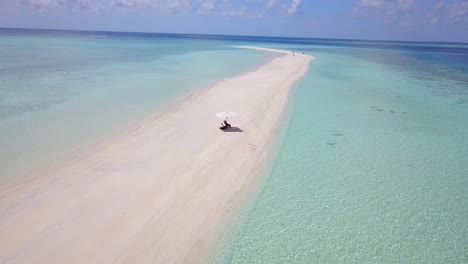 Mann,-Der-Unter-Einem-Regenschirm-Auf-Einer-Einsamen-Sandinsel-Mitten-Im-Indischen-Ozean-Ruht,-Langsame-Luftschwenkung-4k