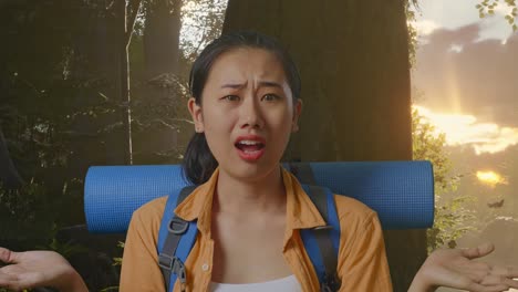 close up of puzzled asian female hiker with mountaineering backpack making gestures doubtfully and saying why while exploring forest nature
