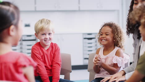 Infant-school-kids-and-teacher-having-a-group-high-five-in-class-after-learning,-selective-focus