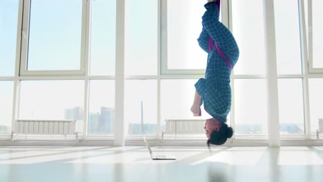 woman in inversion yoga pose with laptop