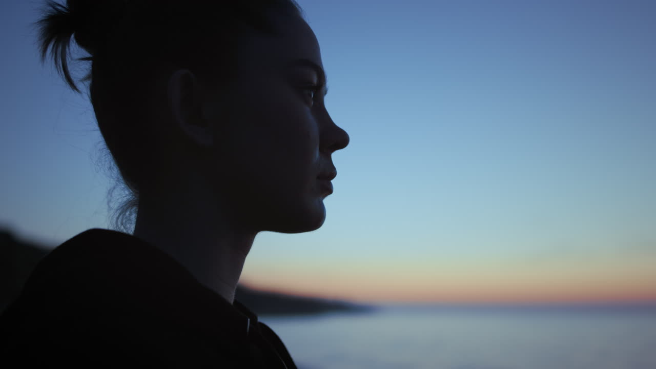 silhueta de mujer de cerca de pie en la playa al atardecer. niña de yoga disfrutando del cielo azul.
