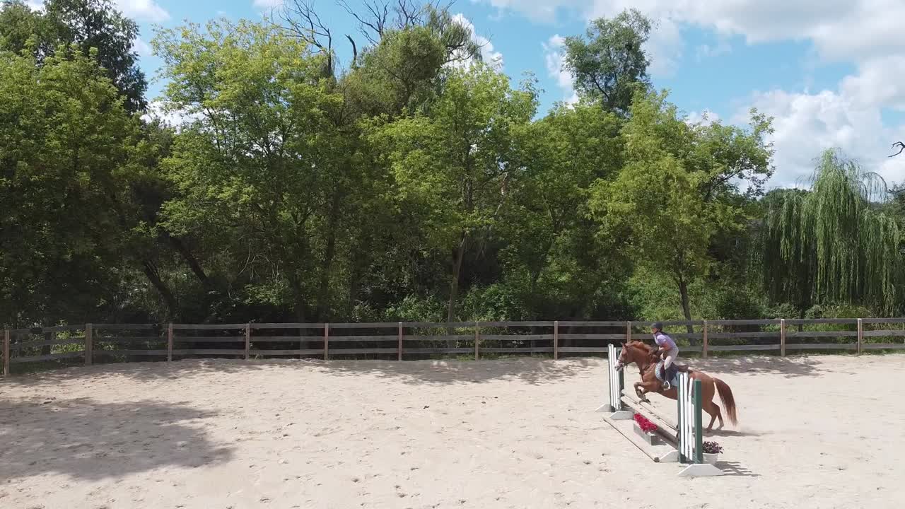 Um plano estático de cima de um pónei e cavaleiro saltando num cenário de verão do Centro-Oeste.
