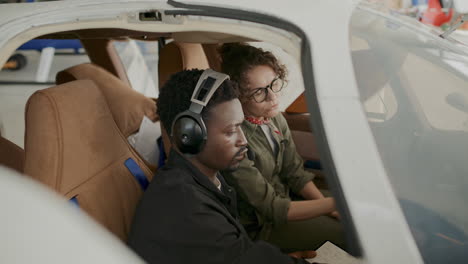 two pilots discussing aircraft controls in cockpit during flight preparation