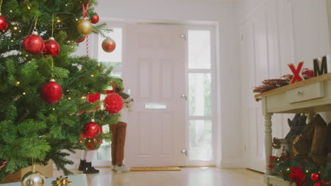 grandchildren greeting grandparents as they arrive with presents to celebrate family christmas