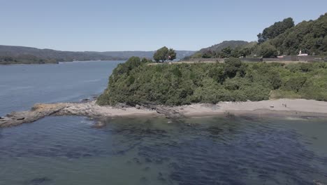 push out aerial shot of a chilean flag in "mancera" island with surrounded by trees, rocks and water