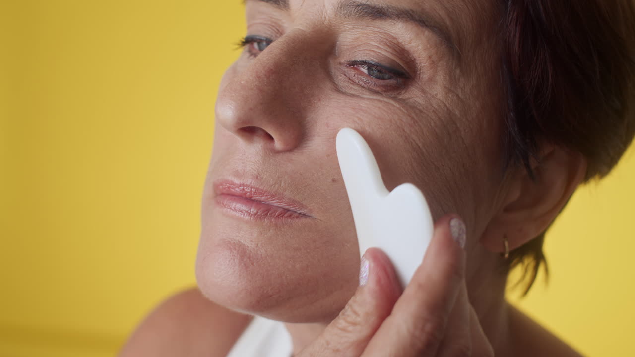 Mature Woman Doing Facial Massage with Gua Sha