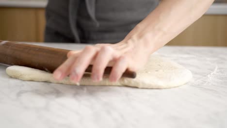 anonymous woman rolling dough for pizza