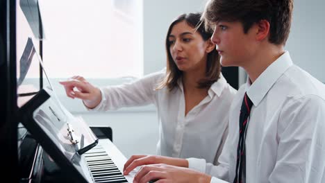 alumno con el profesor tocando el piano en la lección de música