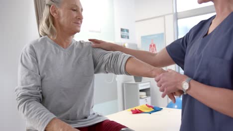 Caucasian-female-physiotherapist-stretching-hand-of-female-senior-patient-at-rehab-center