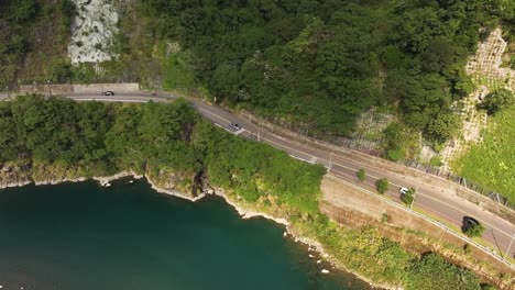 Luftaufnahme-Von-Oben-Nach-Unten-Von-Autos-Auf-Der-Straße-In-Der-Nähe-Des-Flusses-In-Den-Wulai-Bergen-An-Einem-Sonnigen-Tag,-Taiwan---Tourismus-Im-Dorf-Mit-Parkenden-Bussen