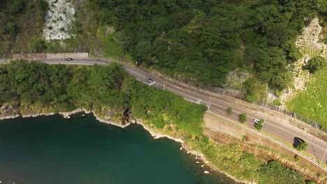 fotografía aérea de autos en la carretera cerca del río en las montañas de wulai en un día soleado, taiwán - turismo en el pueblo con autobuses estacionados