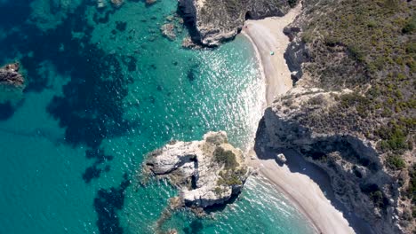 aerial view over kaladi beach with crystal clear waters and sun reflection in kythira island, greece