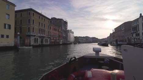 view from the front of a vaporetto boat during sunrise in gran canal of venezia with empty city before tourist crowds invade venice