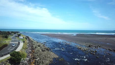 aerial drone shot, flying over a bridge into the river towards the ocean in new plymouth, new zealand.