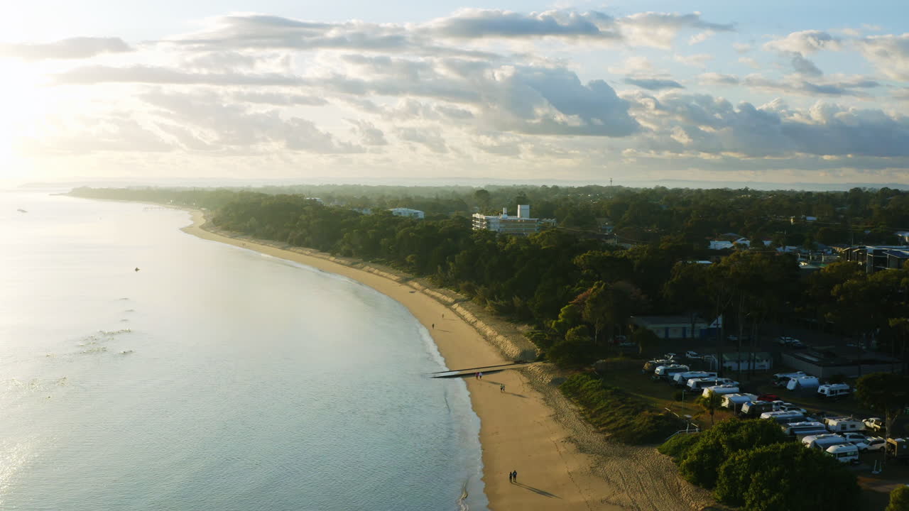 Drone aereo sopra una località balneare costiera e una riva sabbiosa all'alba, Australia 4K