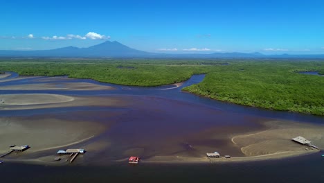 aerial view of tropical estuary with mountains, stilt houses, and motorboats
