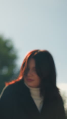 primer plano de una mujer ajustando su cabello mientras se balancea, con la luz del sol reflejándose en ella y la vegetación exuberante en el fondo, capturando un momento de paz