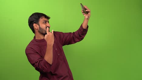 handsome man taking selfy with smartphone, isolated on green screen