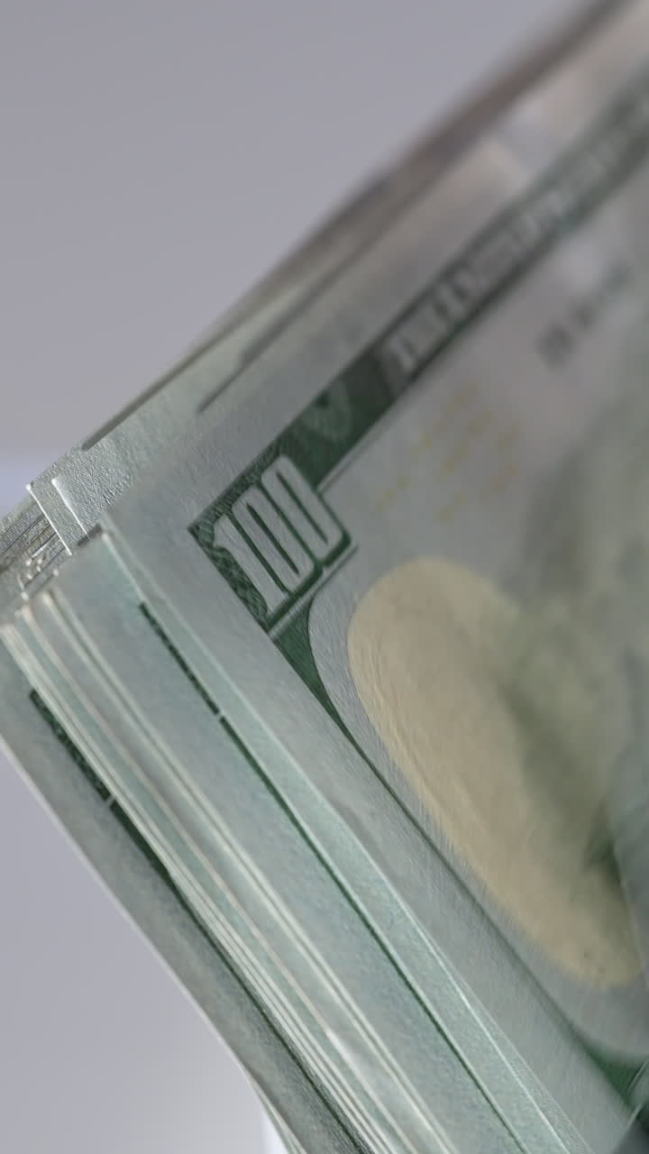 Pile of hundred dollar banknotes in the holder of cash machine. Close up. White background. Vertical video