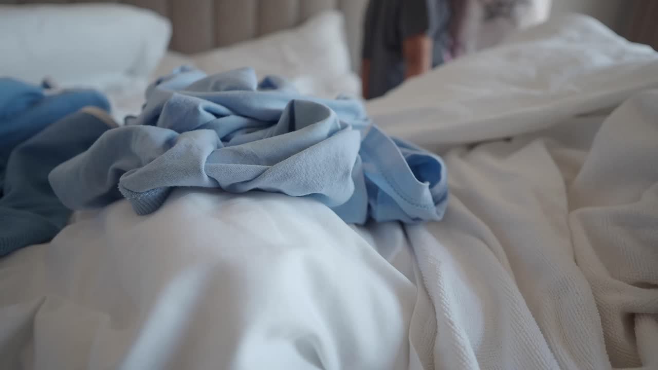 A close-up of a bed with pillows and clothing on it