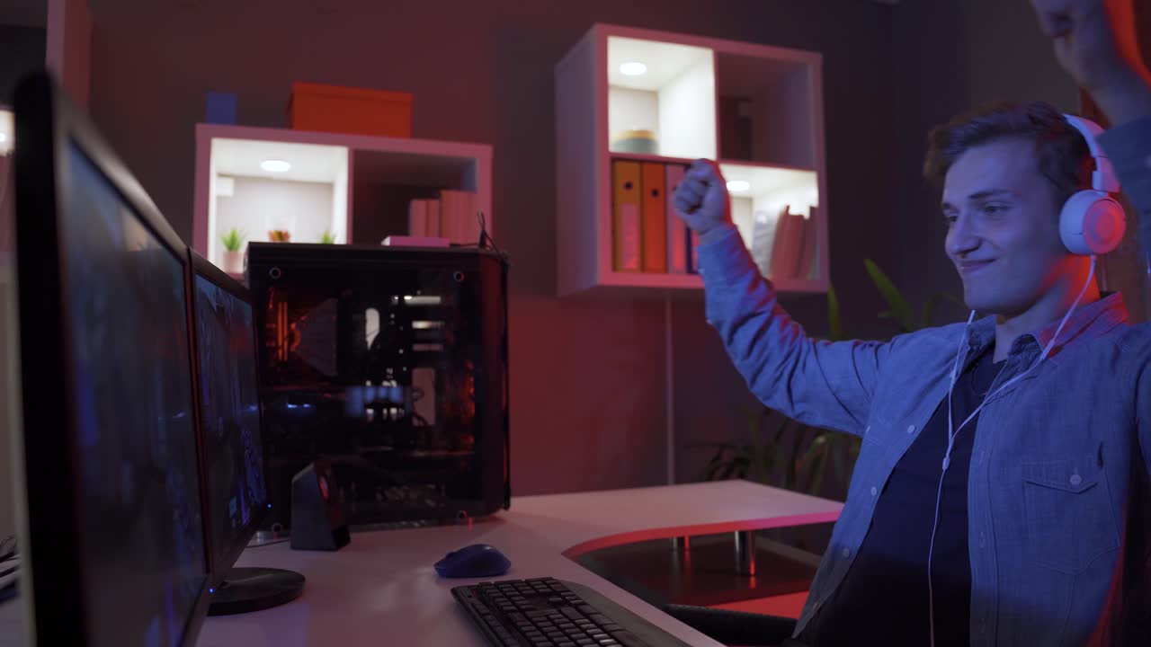 Junger Mann spielt Videospiel am Computer, jubelt und gewinnt