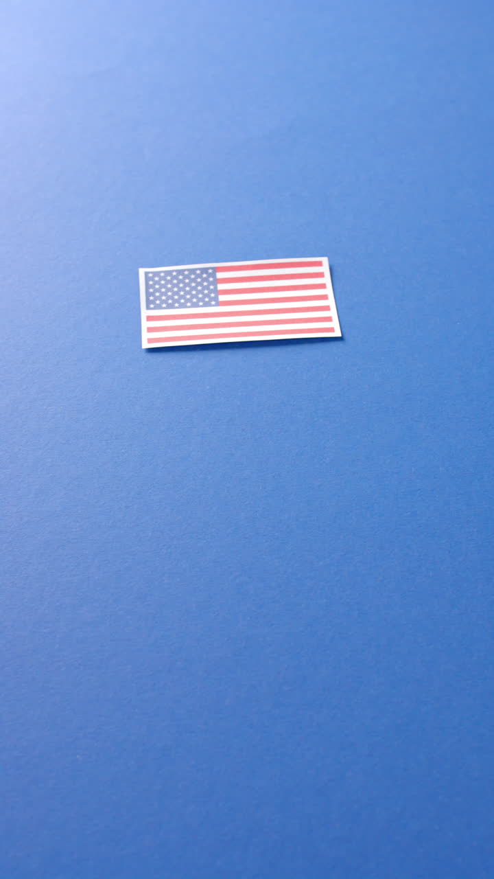 Vertikální video státní vlajky USA ležící na modrém pozadí s prostorem pro text.