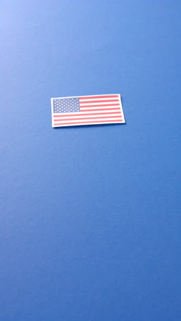 vertical video of national flag of usa lying on blue background with copy space