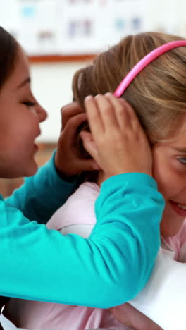 niñas pequeñas contando secretos en el aula.