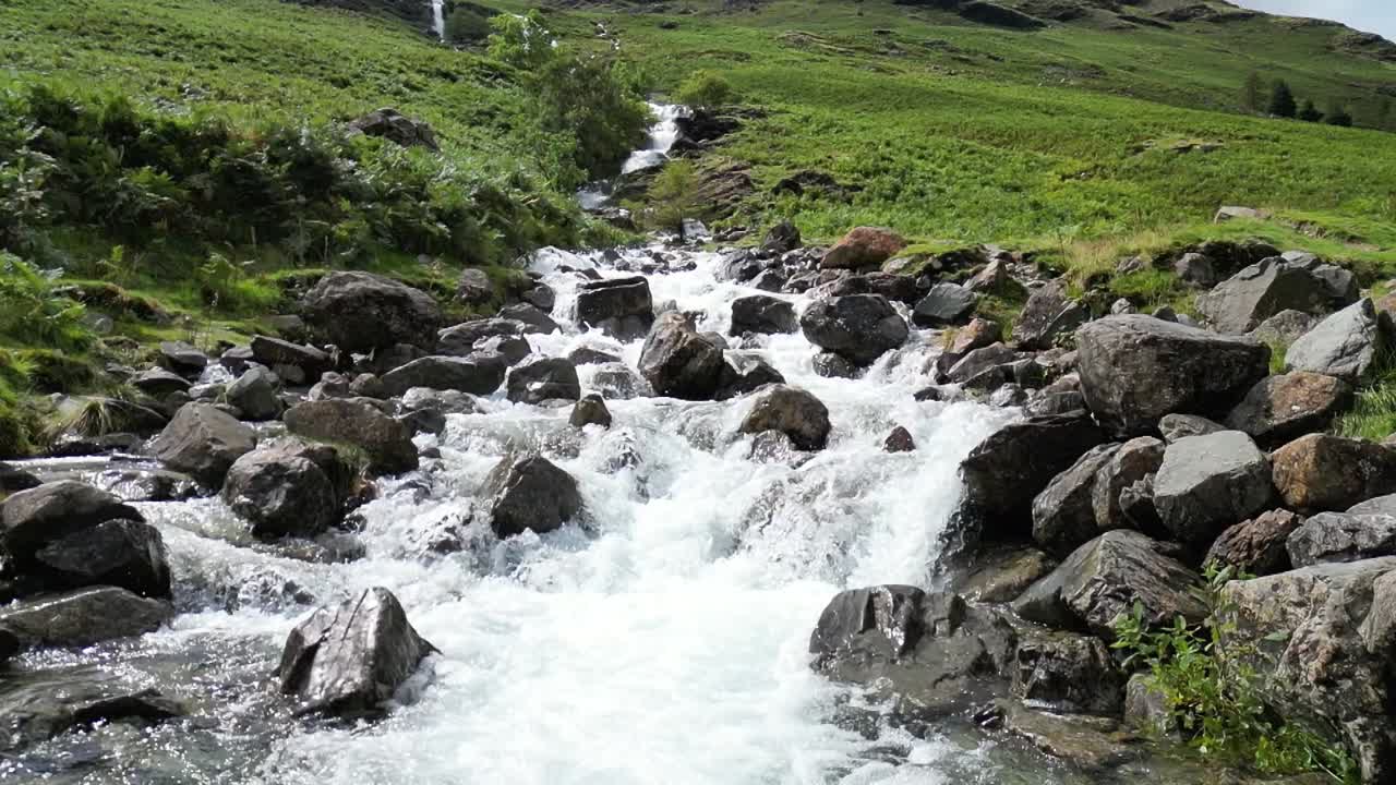la furiosa cascada que cae en cascada por la montaña es en cámara lenta después de días de fuertes lluvias, dron aéreo parte 1 - base de la montaña lenta sobre las rocas, buttermere, distrito de los lagos, reino unido