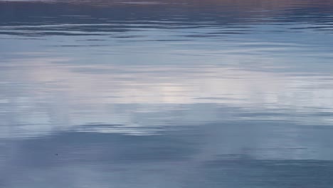 ripples and low waves roll on the glassy surface of the water