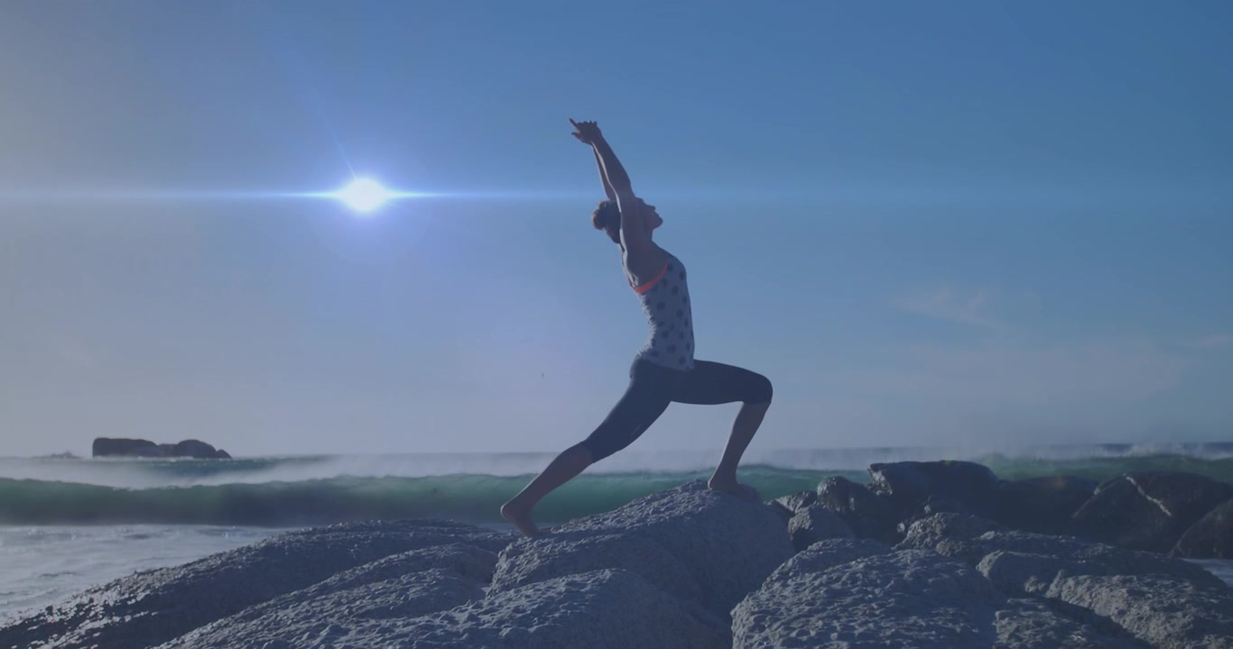 Woman Practicing Yoga Pose on Rocky Beach at Sunset