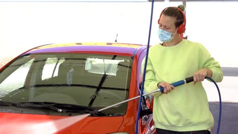 mujer limpiando auto con máscara mientras escucha música, nueva normalidad