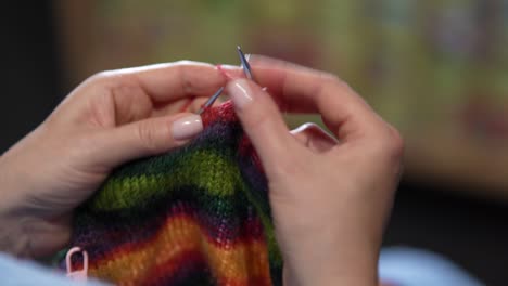 womens hands knit woolen color sweater with knitting needles. top view, close-up of hands and knitting