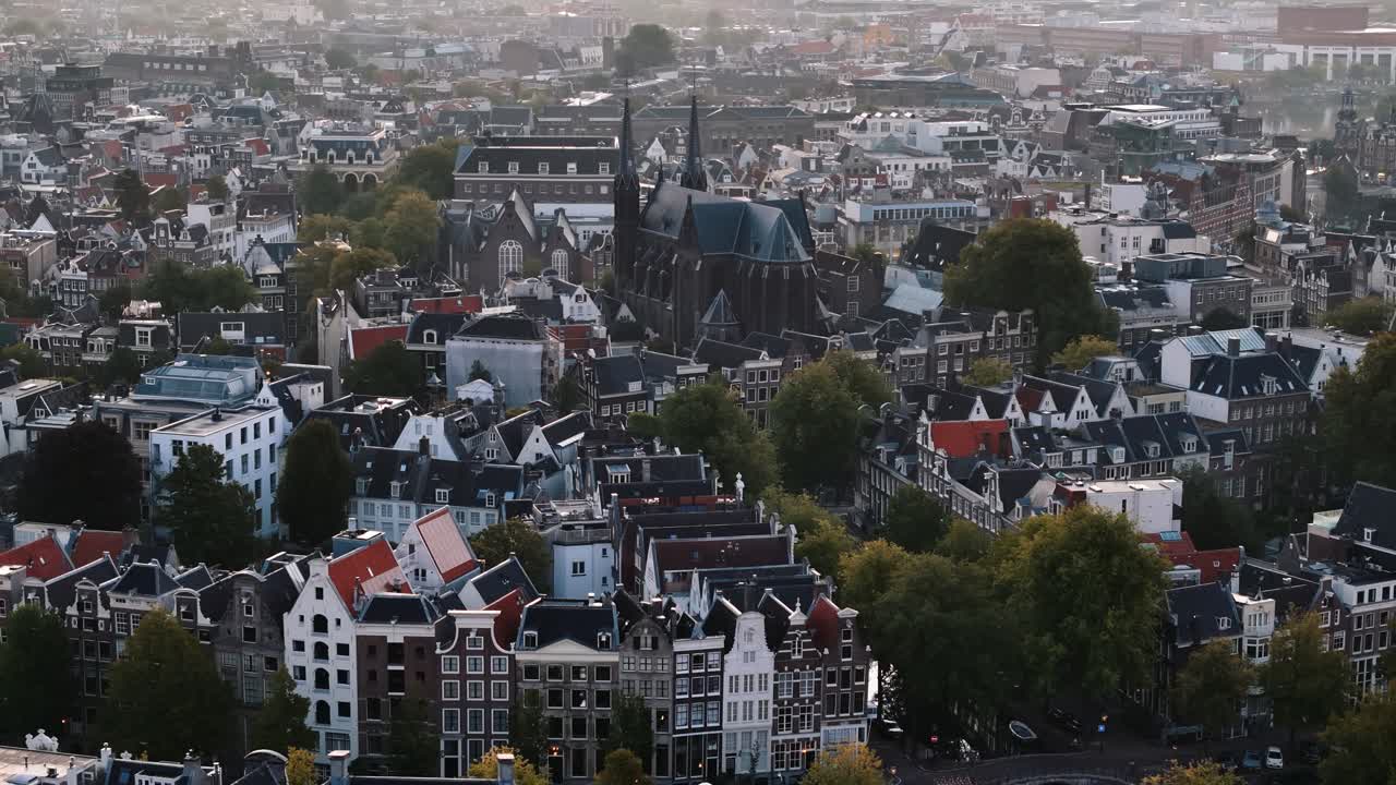 Sunlight spills over a cathedral rooftop in Amsterdam as the city wakes