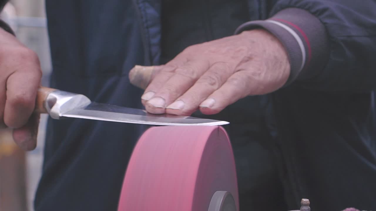 hombre afilando un cuchillo en una rueda de moler