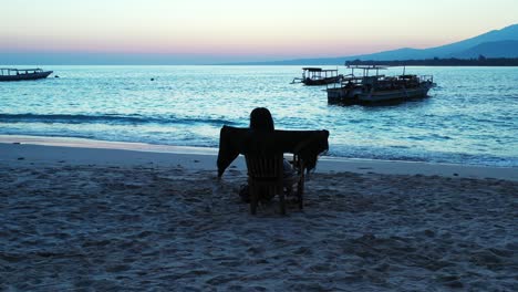 silueta de una joven bruja elaborando la magia en la playa de arena antes del amanecer