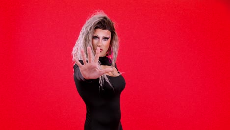 drag queen with hand outstretched on red background