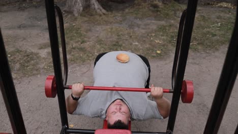 portrait of a young fat man holding a barbell while exercising outdoors the problem of losing weight portrait of a young fat man holding a barbell while exercising outdoors the problem of losing weight in a man