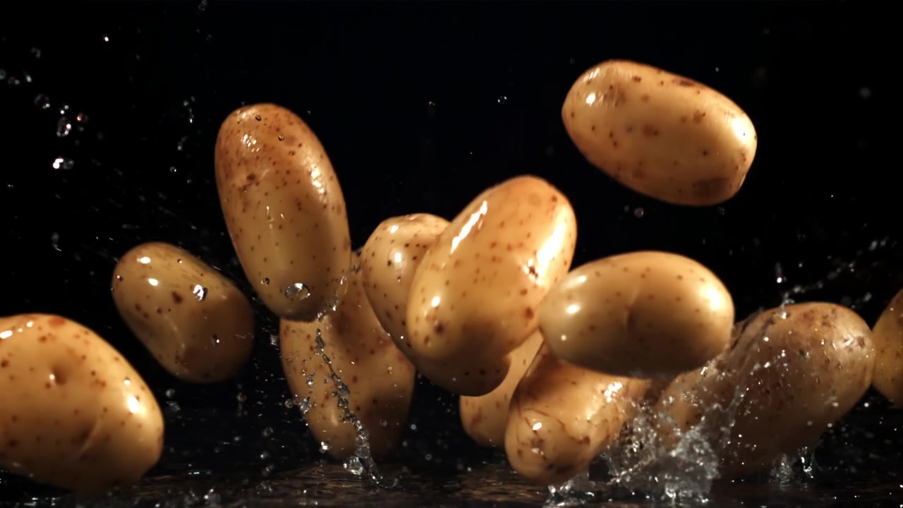 Patate fresche che cadono nell'acqua con schizzi su sfondo nero