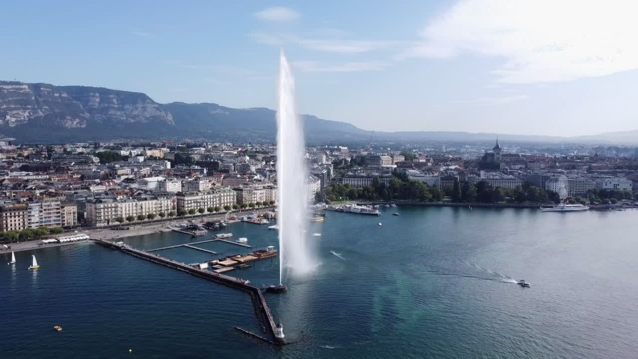 Aerial flying backwards from Jet d'Eau fountain on sunny day, Geneva pier