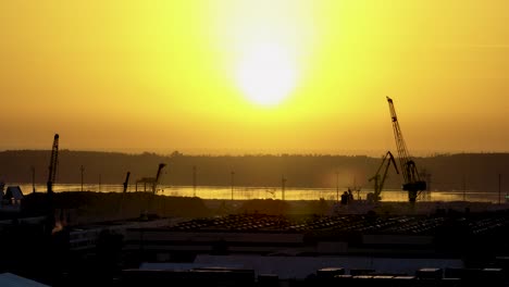 A-beautiful-view-of-the-silhouettes-of-cranes-and-buildings-standing-in-the-port-area-on-a-calm,-sunny-evening