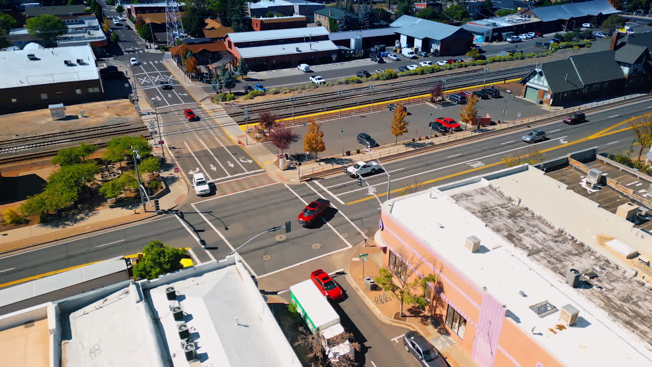 Approaching a little railway station in Flagstaff, Arizona, USA. Multiple cars move by the roads of the city. Aerial view