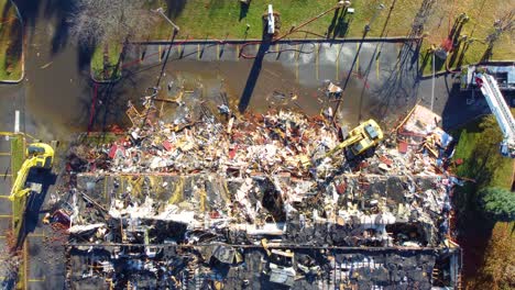 aerial shot of firefighters and excavators working in a destroyed building after a fire in quebec, canada