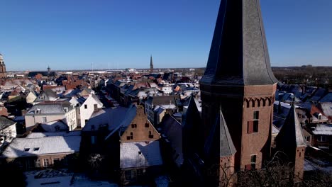 Rotating-aerial-movement-showing-closeup-of-cants-of-Droogenapstoren-city-entrance-tower-in-Hanseatic-Dutch-town-Zutphen-in-The-Netherlands-with-white-from-snow-historic-heritage-buildings-behind