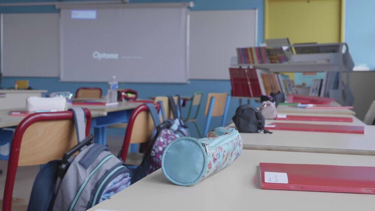 Aula escolar de primaria vacía en Francia, primer plano de un pupitre.