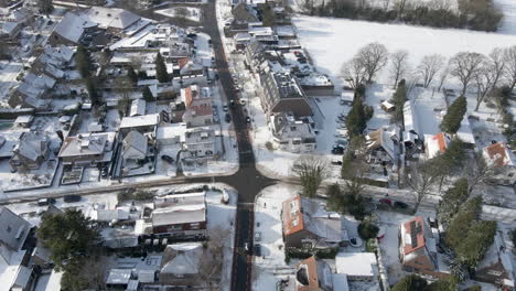 aerial of car driving over clean road in small snow covered town