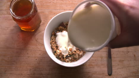 point of view shot of pouring muesli and yogurt into bowl