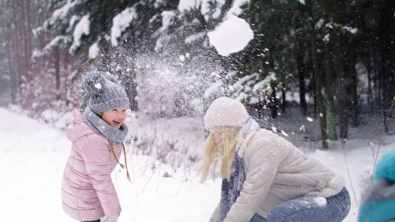 video de una madre y dos hijos luchando con bolas de nieve