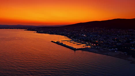 Sea resort in Bulgaria at dusk time. View on the beautiful coast with yacht club. Mountain silhouette at the backdrop of orange sky