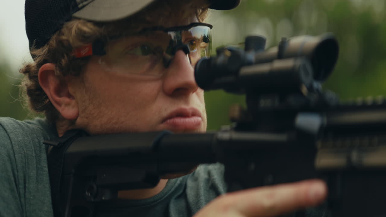 A man wearing glasses with a firearm